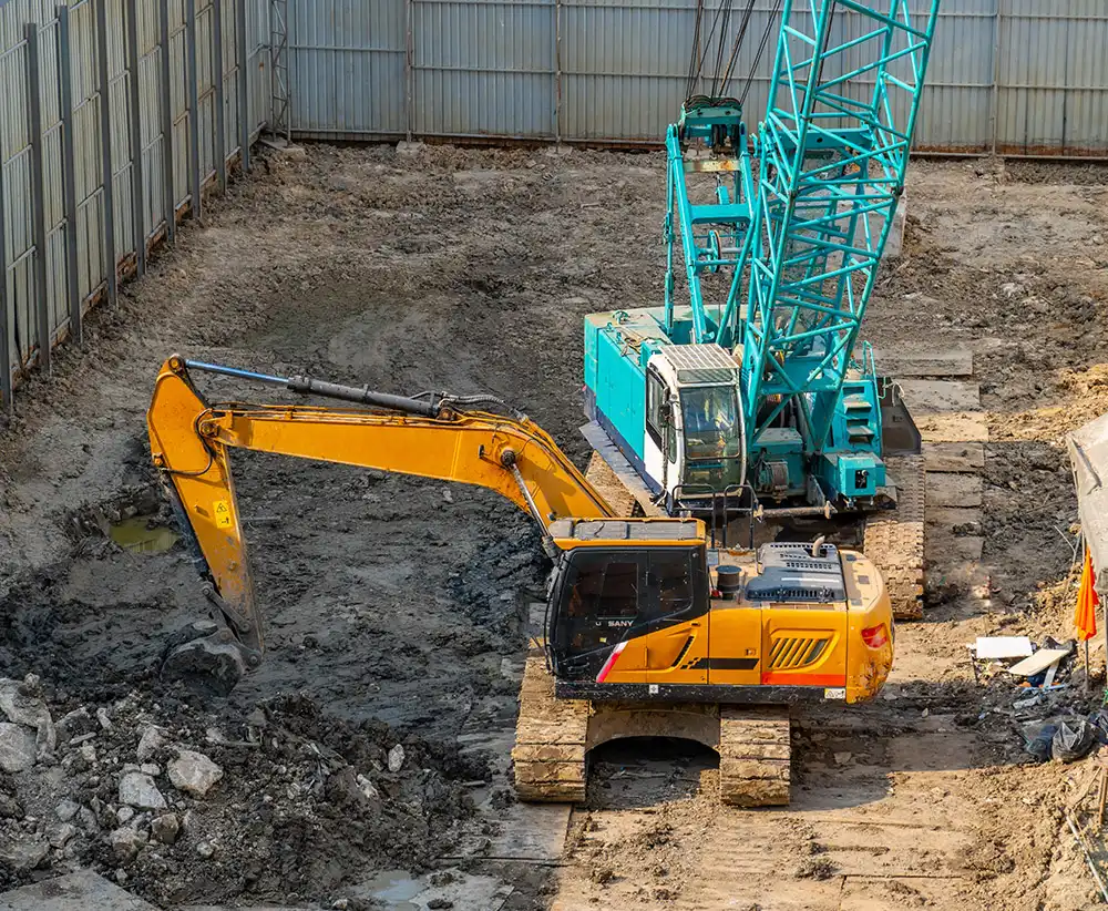 Bagger und Kran bei Erdbauarbeiten an einem Fundament